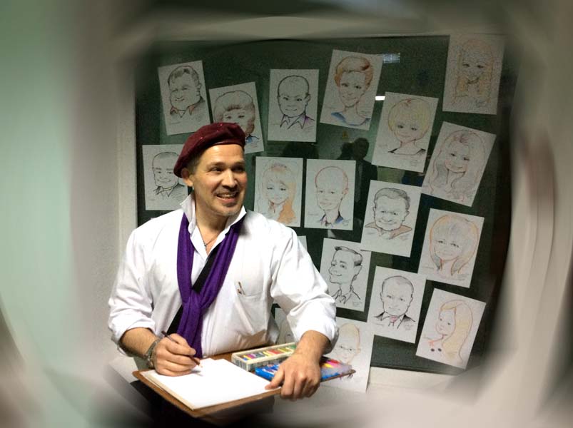 шаржист стоит на фоне выставки шаржей зал Кальварийская на свадьбе